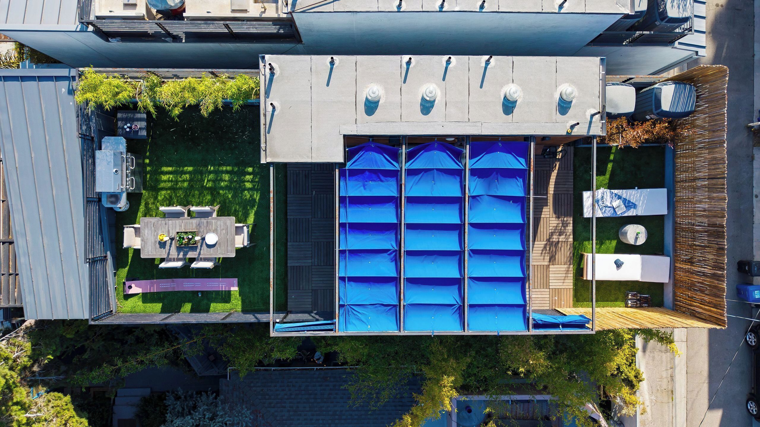 Luchtbeeld van een woonhuis met een zwembad, terras met een tafel en stoelen, en een overdekt buitengebied.