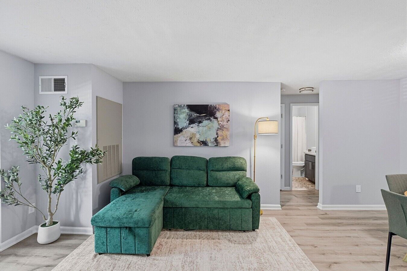 A modern living room with a sectional sofa, a floor lamp, and a painting on the wall.