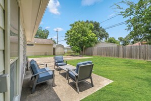 A backyard with a patio area, a wooden fence, and a tree. - Near UH, Rice University, Texas Medical Center & Downtown w/ Game Room (Houston)