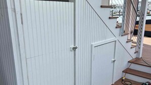 Una terraza de madera con una puerta blanca y una escalera que conduce a un nivel superior.