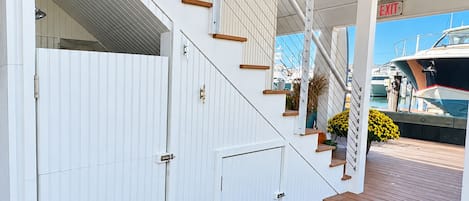 A staircase leading to a covered deck area with a view of boats docked in the background.