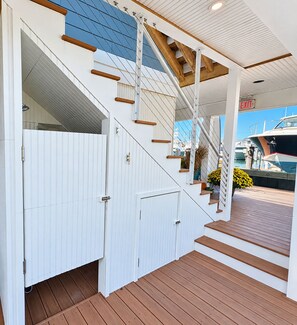 A staircase leading to a covered deck area with a view of boats docked in the background. - Cape May Harbor Getaway with Kayaks & Bikes (Cape May)