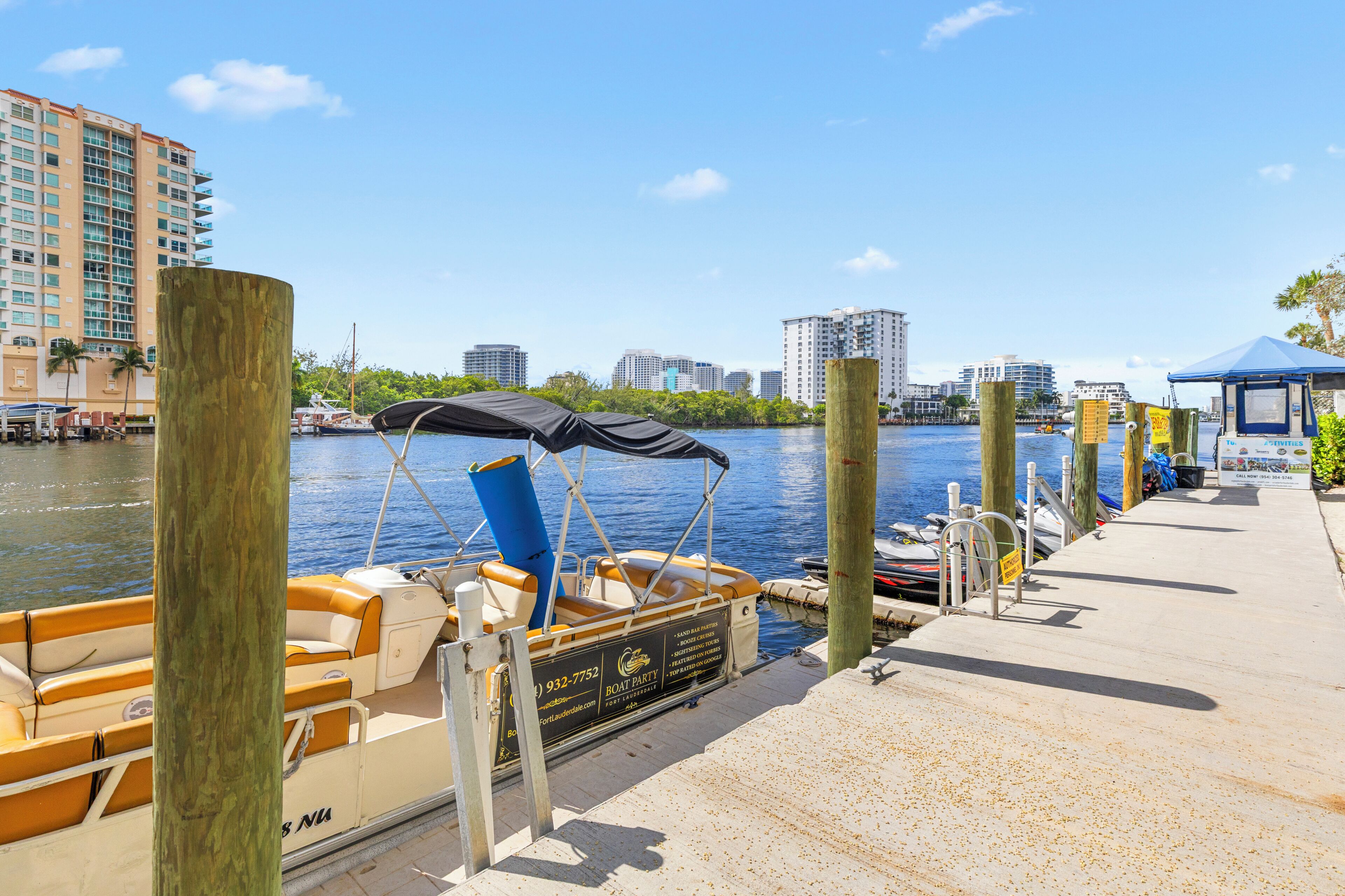 A waterfront dock with boats, a city skyline, and a clear sky.