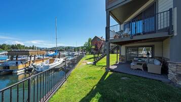A waterfront property with a balcony, a grassy lawn, and a marina with boats.