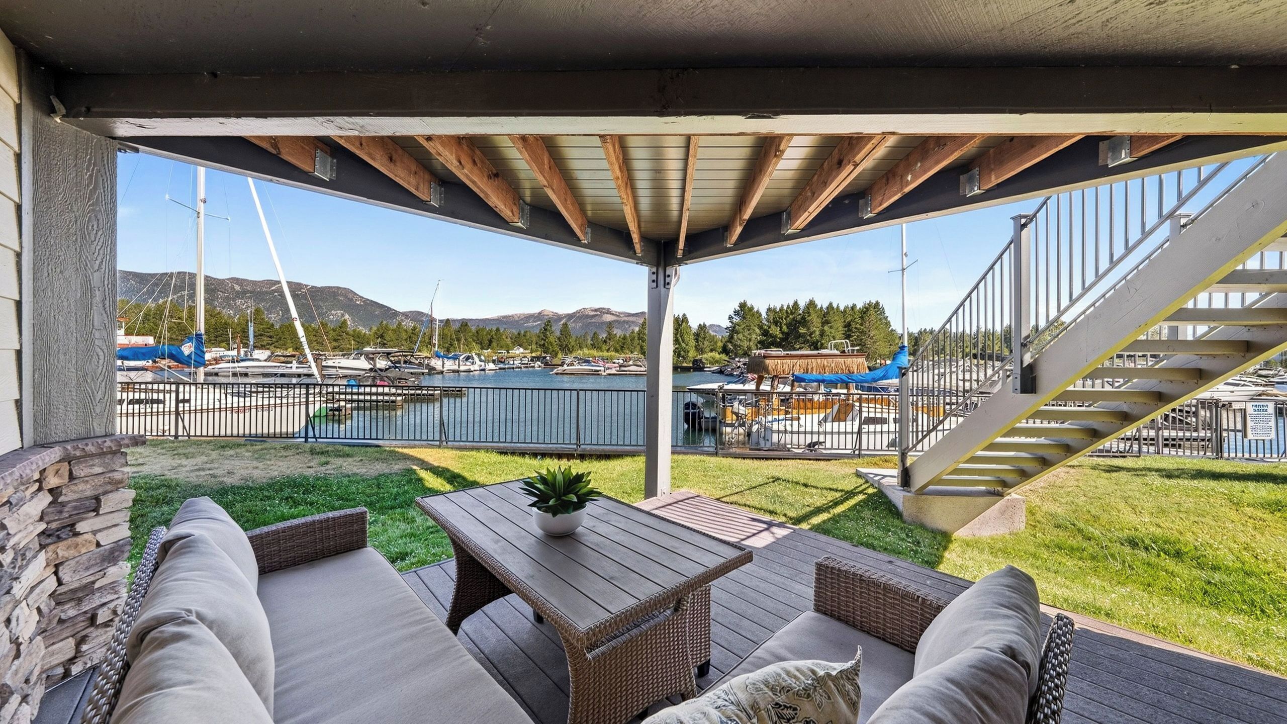 A covered outdoor seating area with a view of a marina and mountains.