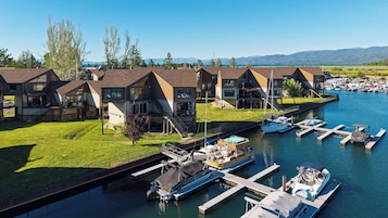 Puerto deportivo con barcos amarrados, una zona verde y una hilera de casas con balcones.