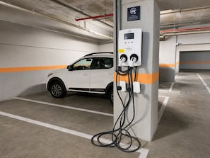 A parking garage with a white car parked near a charging station. - Hosts BR - Studio GAV Resorts (Ipojuca)