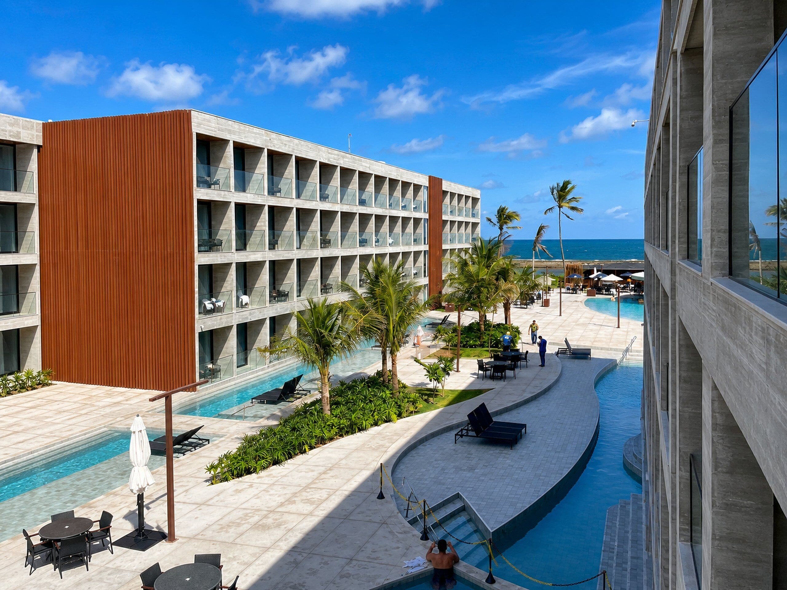 A hotel with a pool, outdoor seating, and a view of the ocean.