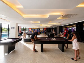 Uma área de mesas de bilhar com várias mesas e jogadores envolvidos em um jogo.