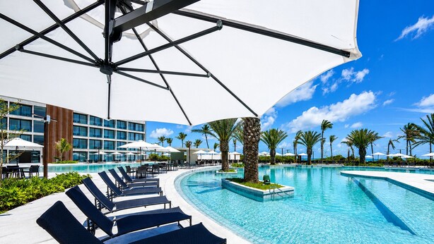 A hotel pool area with lounge chairs, umbrellas, and a clear blue sky. - Hosts BR - Studio GAV Resorts (Ipojuca)