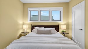 Ein Schlafzimmer mit einem Bett, zwei Nachttischen, einem Fenster und einer Tür.