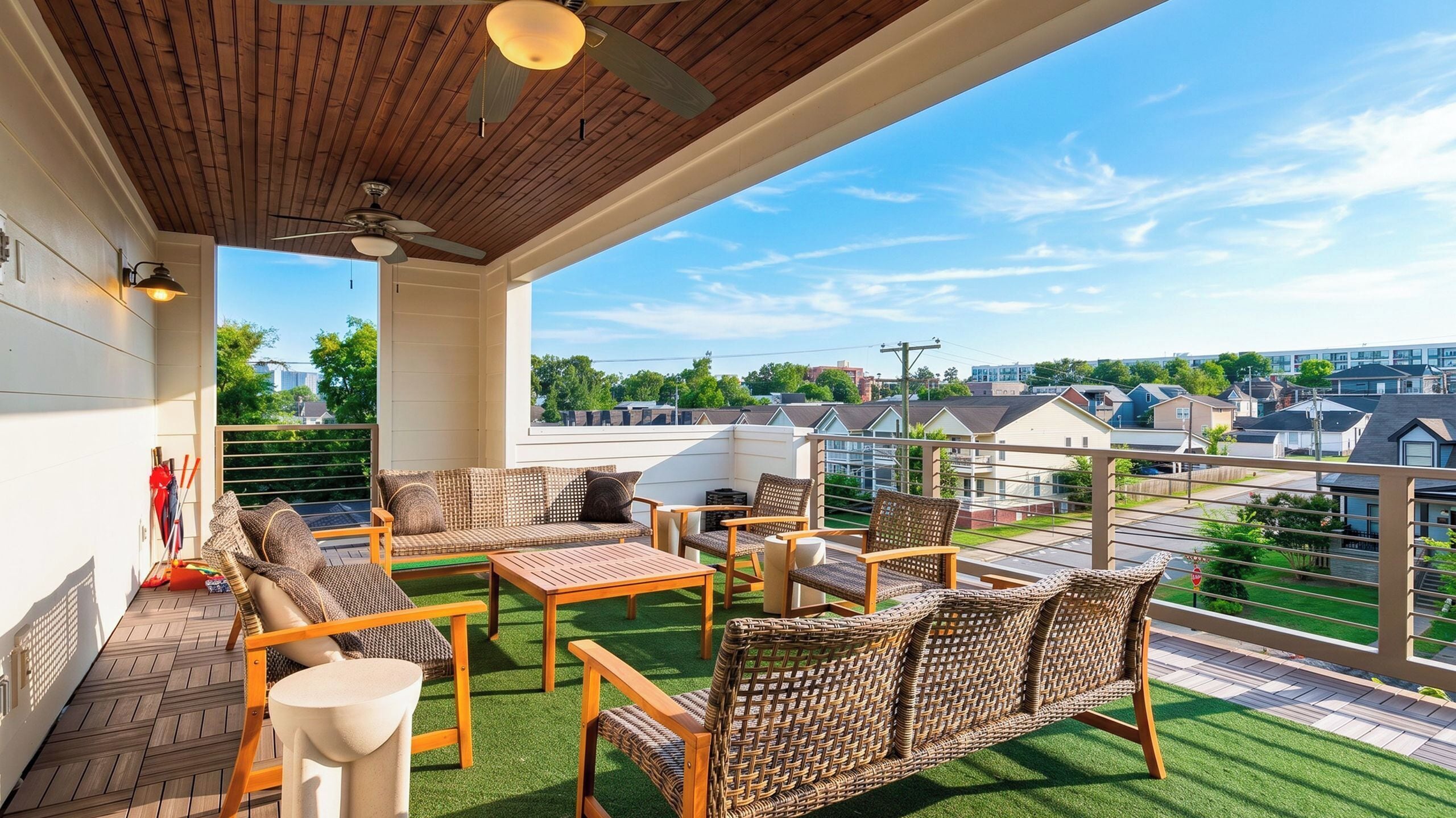 A covered patio with wicker furniture, a ceiling fan, and a view of residential buildings.