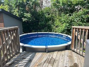 A circular swimming pool with a wooden deck surrounding it. - Stylish 4-Bedroom Home (Gatineau)