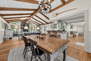 A spacious kitchen with a large wooden island, wooden beams on the ceiling, and a stone fireplace. - Mtn-View Cashiers Cottage w Screened Deck! (Glenville)