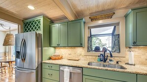 A kitchen with green cabinets, a stainless steel refrigerator, a granite countertop, and a window with a view. - Mtn-View Cashiers Cottage w Screened Deck! (Glenville)