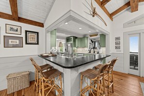 A kitchen with a central island, green cabinets, and a hanging antler. - Mtn-View Cashiers Cottage w Screened Deck! (Glenville)