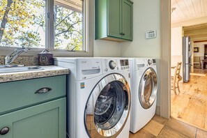 A laundry area with two front-loading washing machines, a sink, and a window with a view of trees. - Mtn-View Cashiers Cottage w Screened Deck! (Glenville)
