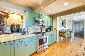Une cuisine avec des armoires de couleur turquoise, une cuisinière en acier inoxydable et un four à micro-ondes.