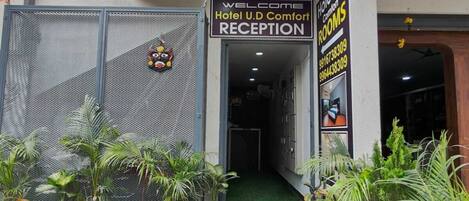A hotel entrance with a sign for 'Hotel U.D Comfort Rooms' and a reception area.