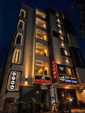 Un hotel de varios pisos con señalización iluminada que dice 'Hotel Ud Comfort Rooms' y 'Spirit Zone'.