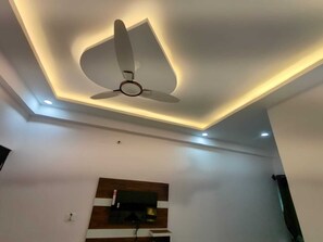Ventilador de techo de diseño moderno, iluminación empotrada y pared revestida de madera.