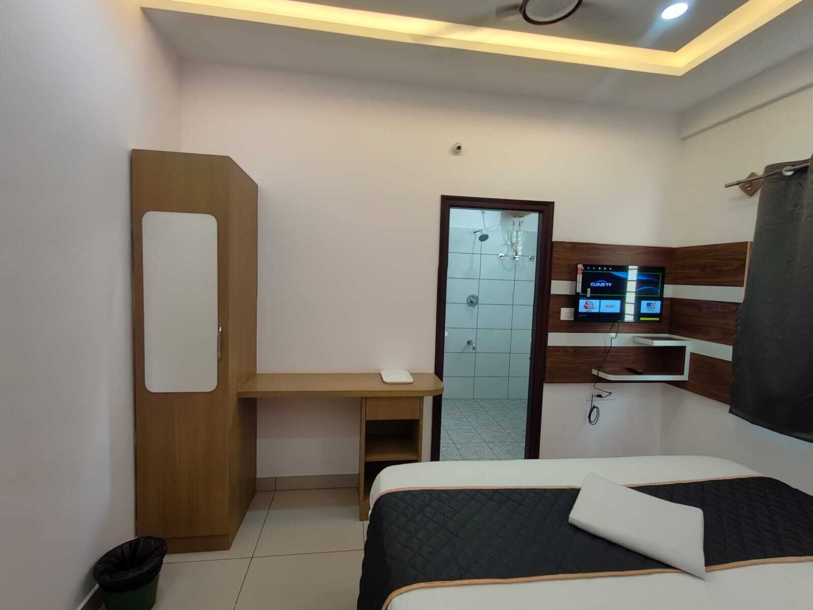 A hotel room with a bed, a desk, a TV, and a shower.