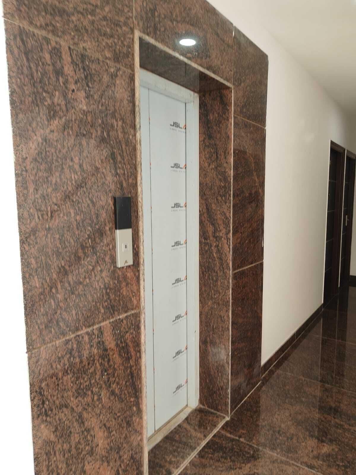 A hallway with a marble wall and a door with a security keypad.