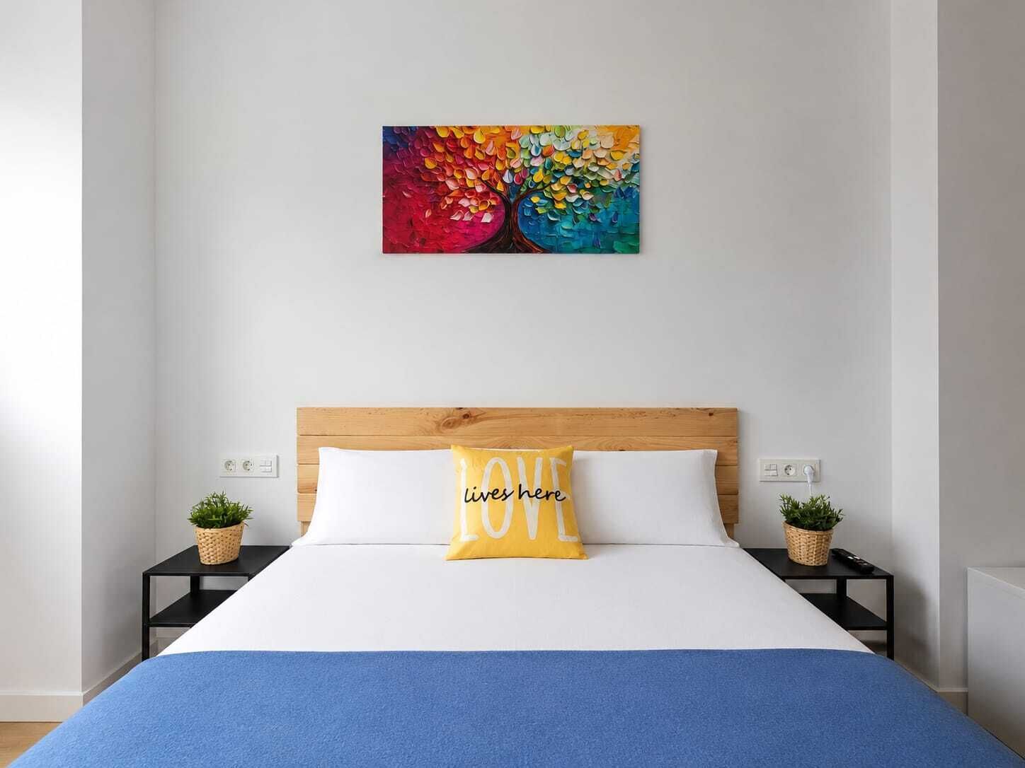 A bedroom with a bed, two bedside tables, a headboard, and a colorful artwork on the wall.