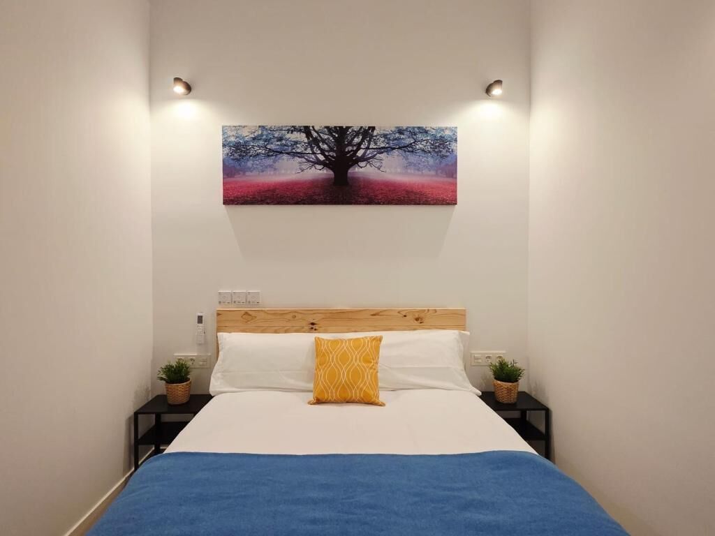 Un dormitorio con una cama, un cuadro en la pared y dos mesitas de noche con lámparas.