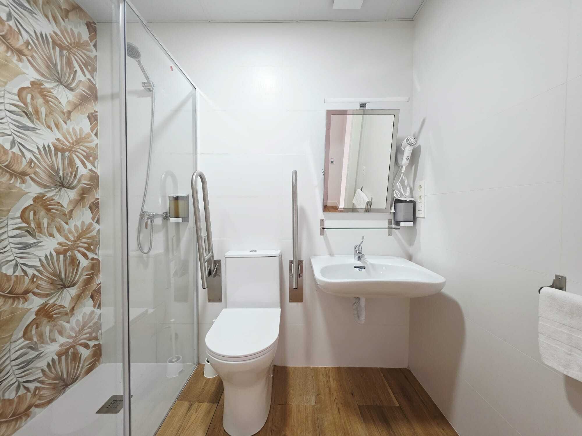 Un baño con cabina de ducha de vidrio, inodoro, lavabo y espejo.
