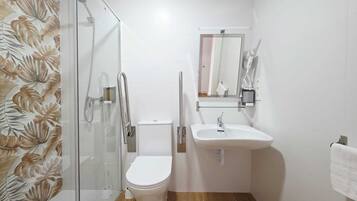 Un baño con cabina de ducha de vidrio, inodoro, lavabo y espejo.