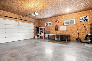 A garage with a white garage door, a dartboard, a table, and a window.