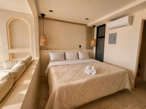 A bedroom with a bed, pillows, a bedside table, a lamp, and an air conditioning unit. - Luxury Beachfront with King Bed & AC (Tijuana)