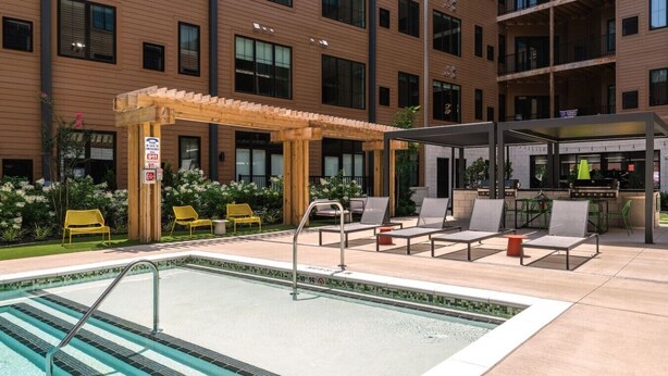 Area piscina con pergola, poltrone a sdraio e una zona relax coperta.