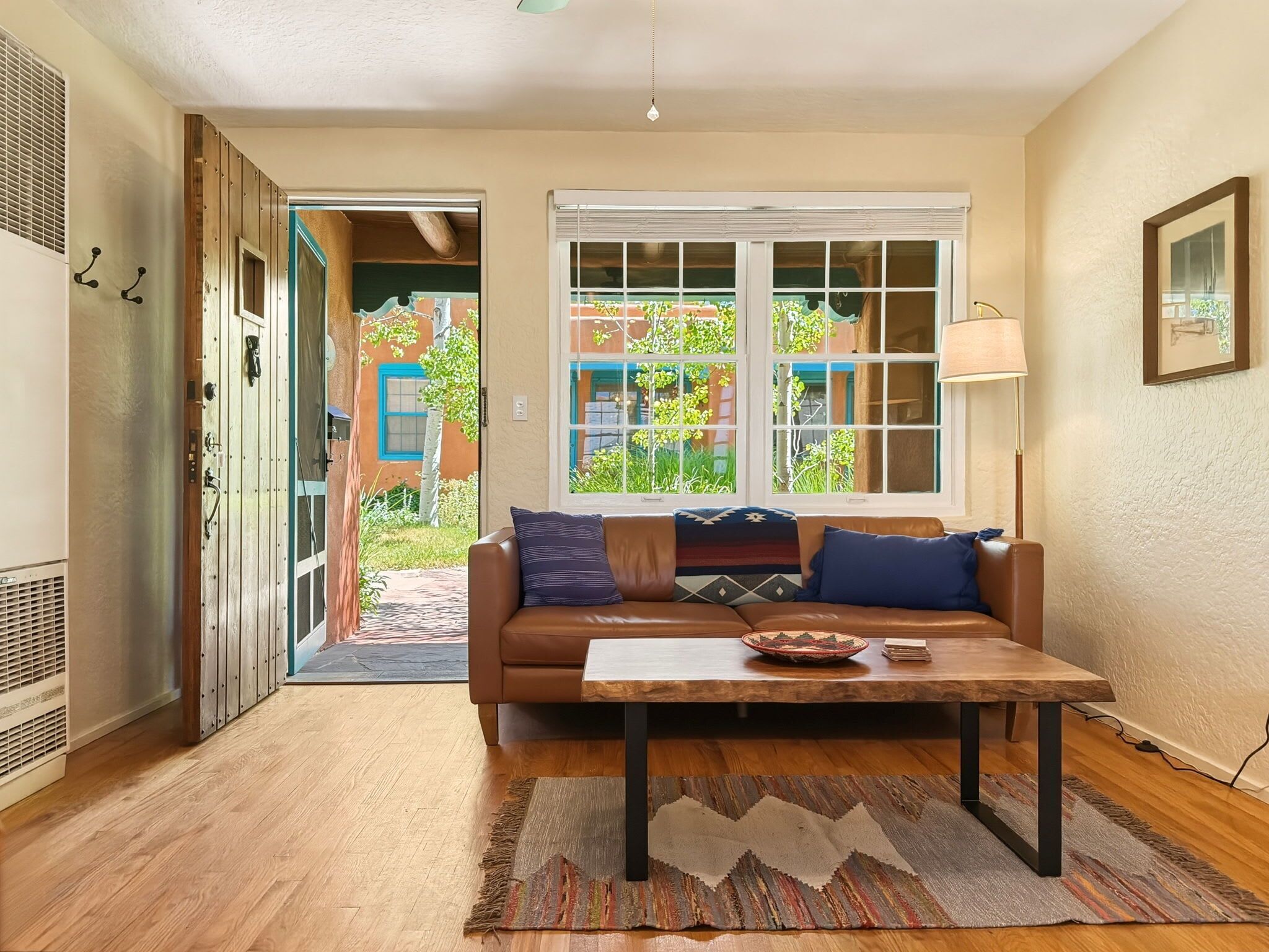 A living room with a brown leather sofa, a wooden coffee table, and a patterned rug.