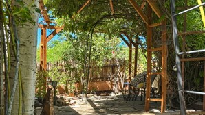 Ein überdachter Außenbereich mit Steinböden, einer Holz-Pergola und Sitzgelegenheiten.