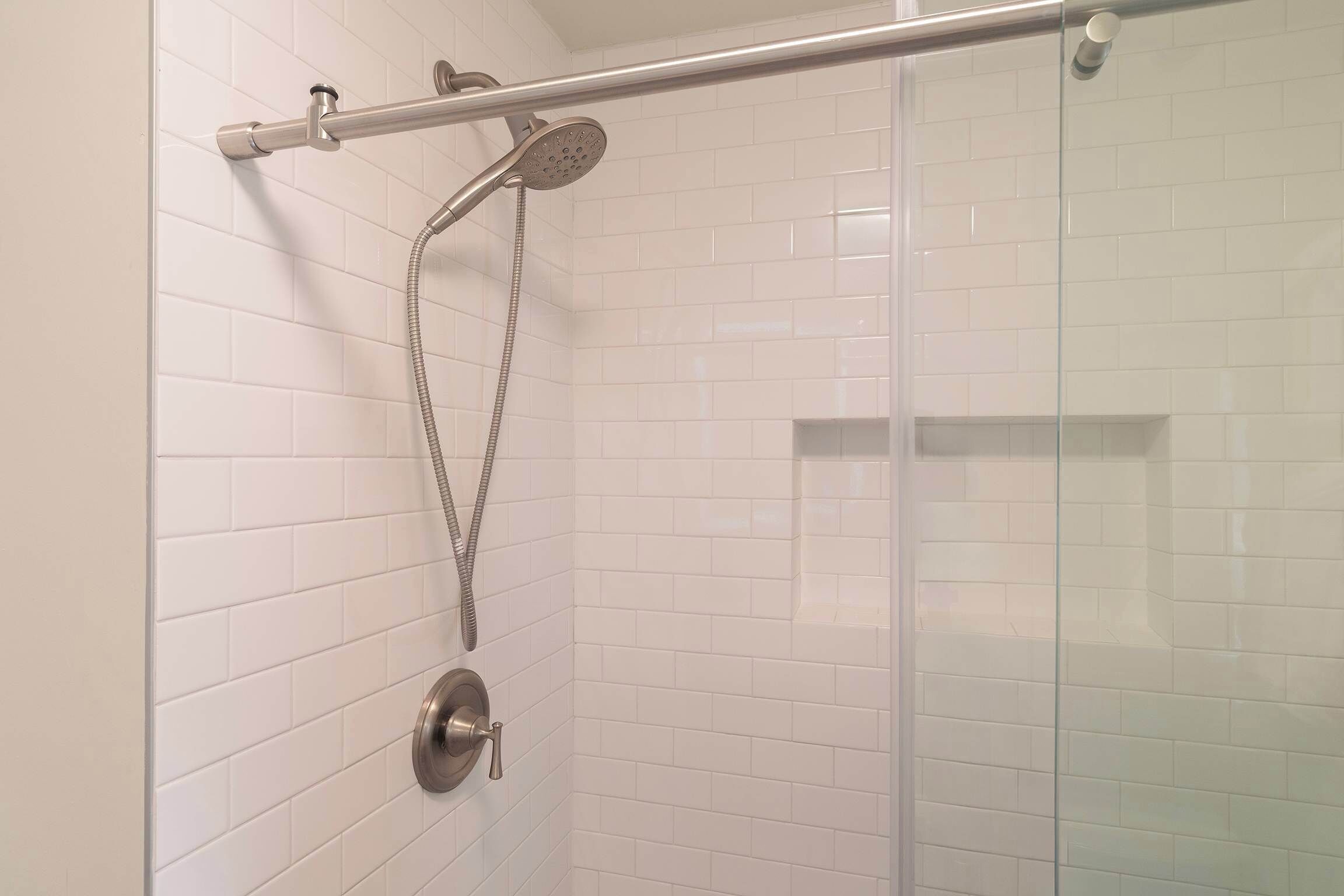 Een douche met een handdouche en een handslang.