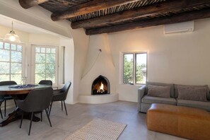 A room with a fireplace, a dining table with chairs, a sofa, and a window. - Sunset Mountain Casita - 1 Bedroom (Santa Fe)