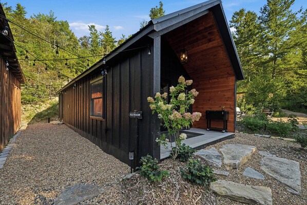 A cabin with a wooden exterior, a visible restroom sign, and a gravel driveway.