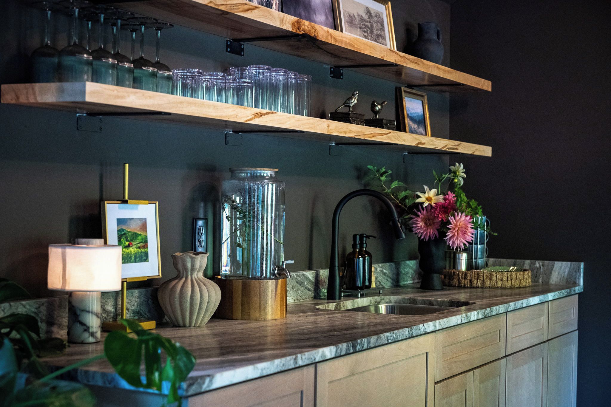 Eine Küche mit Holzböden, einer Spüle, einer Blumenvase und einer Lampe.