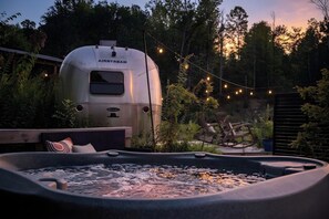 Un jacuzzi con vistas a una caravana identificada con el rótulo 'AIRSTREAM' al fondo.