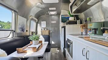 A compact kitchen with a stove, microwave, and a coffee maker.