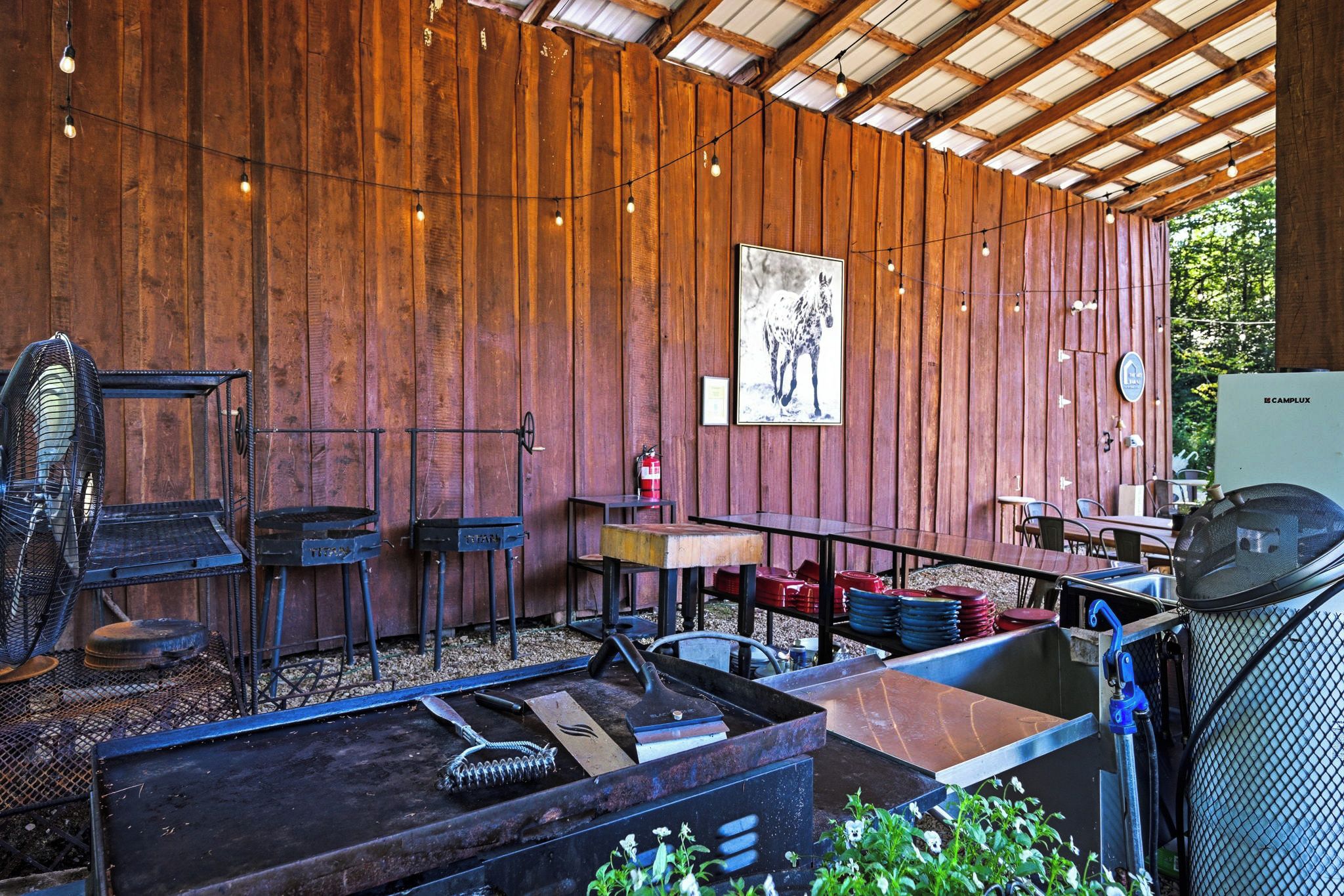 A rustic outdoor dining area with wooden walls, metal furniture, and a fire extinguisher.