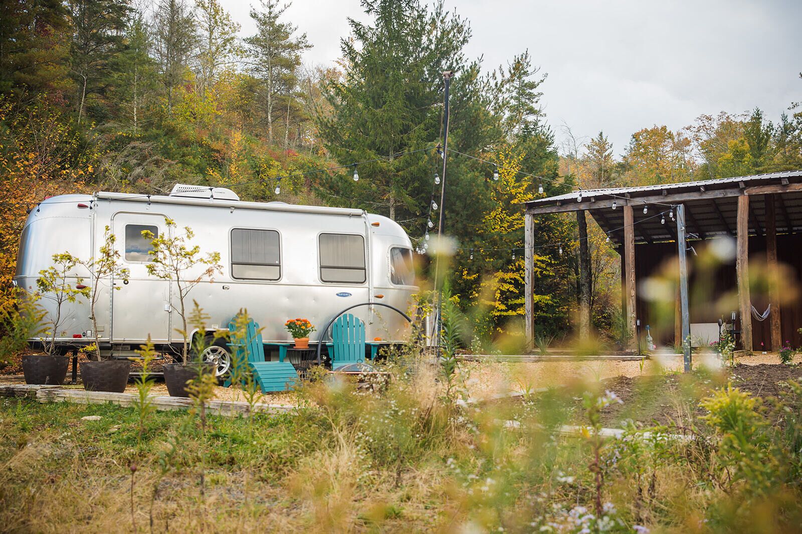 A white RV parked in a natural setting with a covered outdoor area.