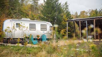 A white RV parked in a natural setting with a covered outdoor area.