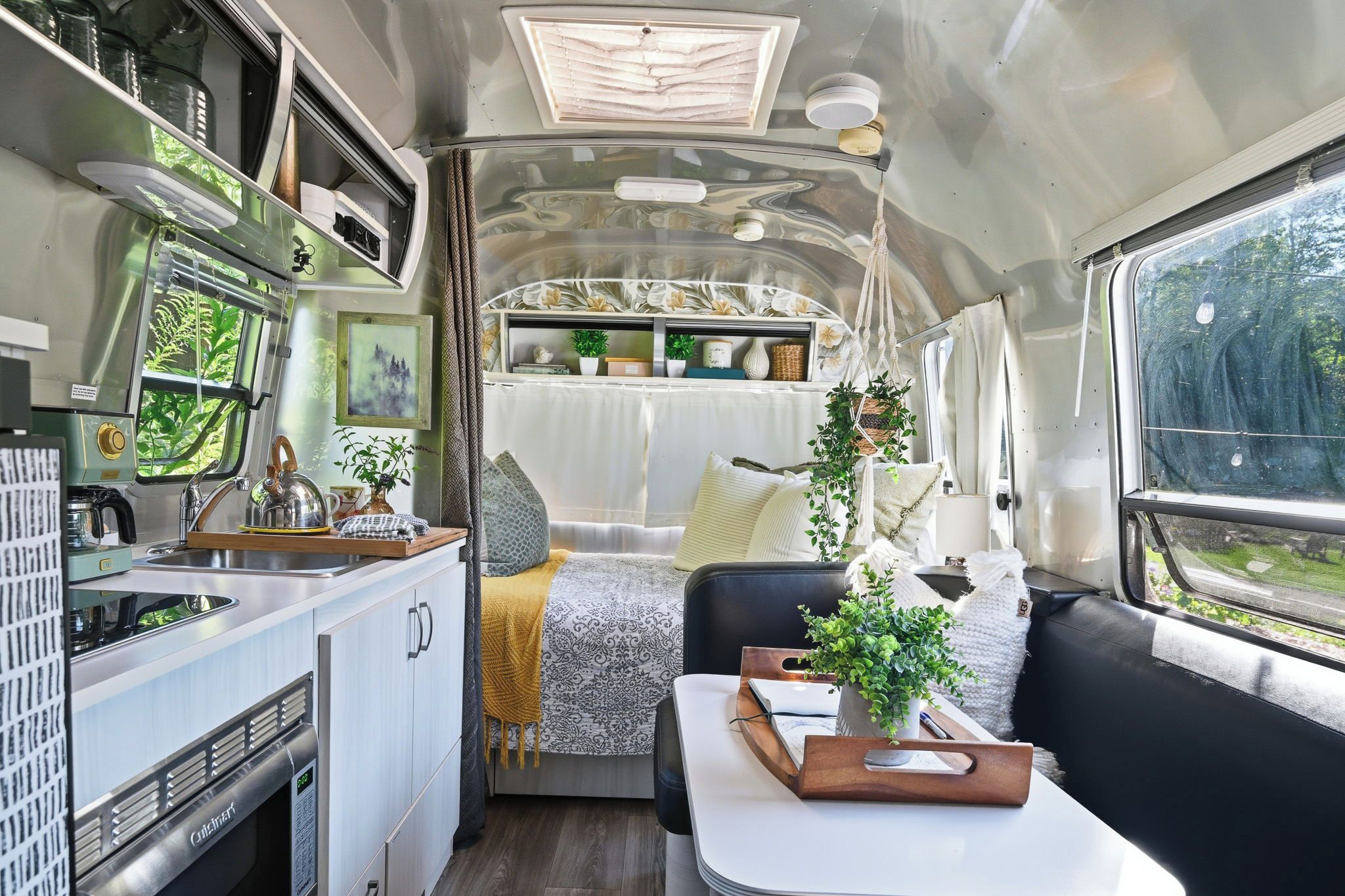 A compact RV interior with a kitchenette, a dining area, and a sleeping berth.