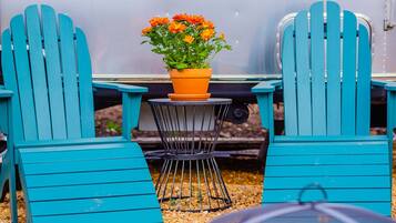 Two turquoise Adirondack chairs, a small round table with a potted plant, and a metal chair with a round table.