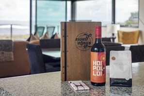Una botella de vino, una caja y un paquete de bocadillos sobre una mesa con vista al mar.