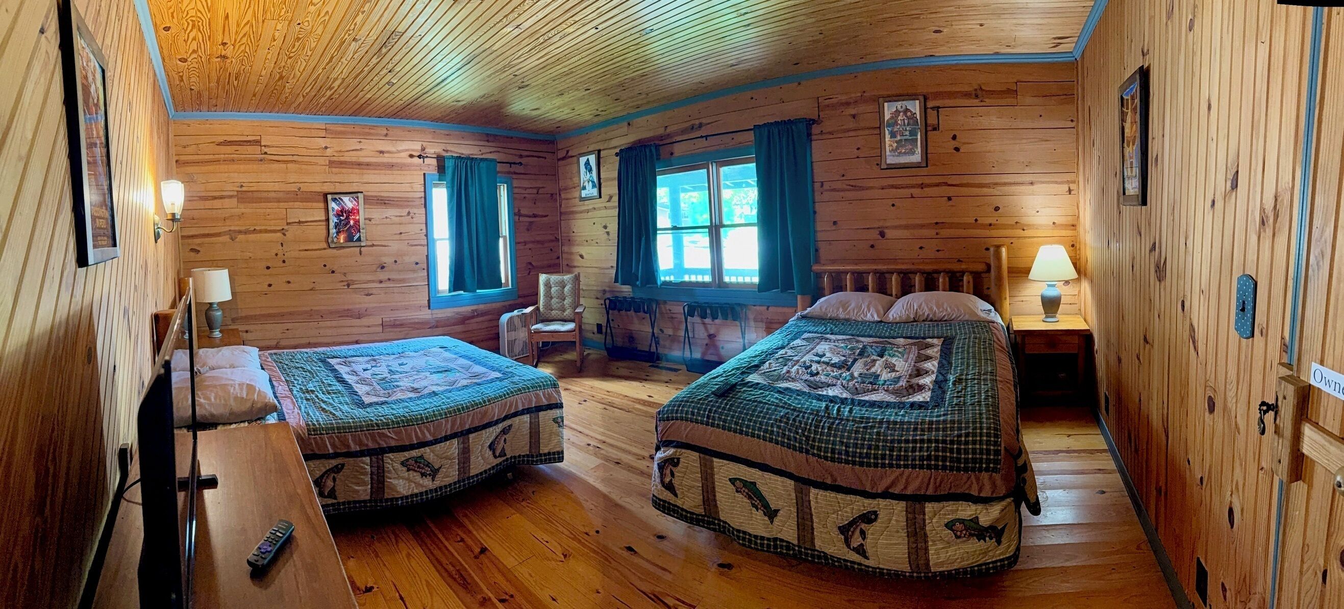 A cabin-style room with two beds, a chair, a table, and a window.