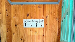 A wooden room with a bench, a 'welcome to our home' sign, and a patterned rug. - Log Cabin 2-bedroom lake view 20 minutes to Branson (Forsyth)